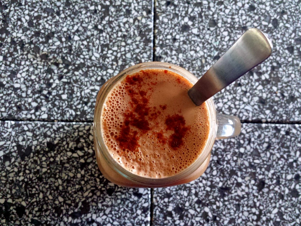 Mug of tea  with a spoon, with coconut milk, and a sprinkle of cinnamon